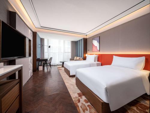 a hotel room with two beds and a flat screen tv at Hilton Garden Inn Beijing Guomao in Beijing