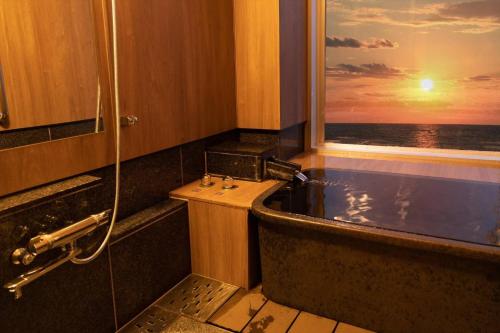 a bathroom with a bath tub and a window at Ikkyu -Seaside Hotel- in Tsuruoka