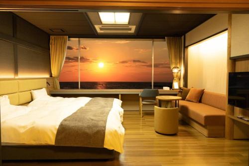 a bedroom with a bed and a window with a sunset at Ikkyu -Seaside Hotel- in Tsuruoka