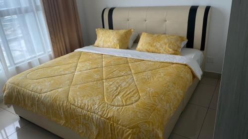 a bed with a yellow comforter and two pillows at Homestay Lakepark in Batu Caves