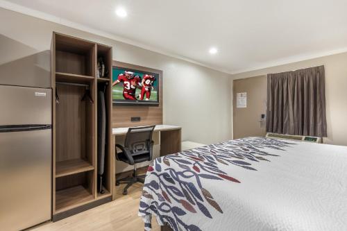 a bedroom with a bed and a desk and a refrigerator at Red Roof Inn Raleigh Northeast - Downtown in Raleigh