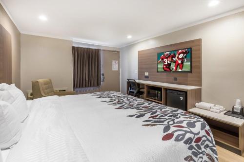 a hotel room with a large bed and a desk at Red Roof Inn Raleigh Northeast - Downtown in Raleigh