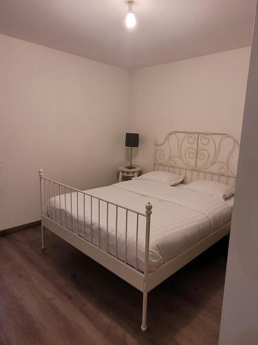 a white bed in a room with a lamp on a table at Le central grenoblois in Grenoble