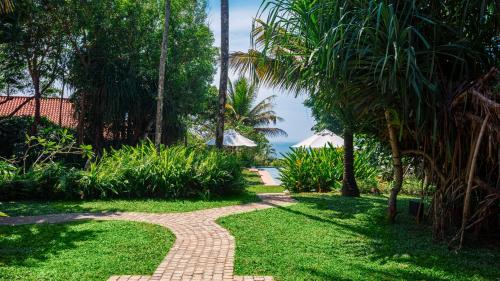 a brick path through a garden with palm trees at Cape Weligama - Relais and Chateaux in Weligama