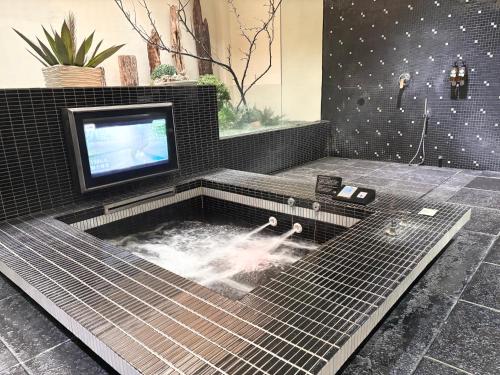 a bathroom with a tub with a tv in it at Xiadu Motel in Taichung