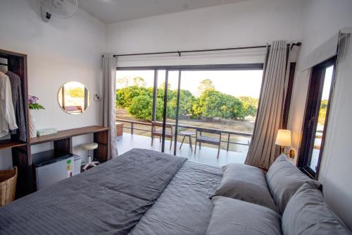 a bedroom with a large bed and a large window at The Farmer Farm Stay & Cafe in Chom Thong