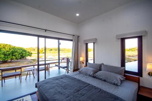 a bedroom with a large bed and a balcony at The Farmer Farm Stay & Cafe in Chom Thong