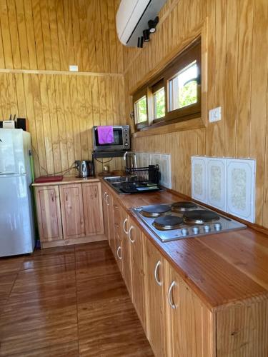 a kitchen with wooden cabinets and a white refrigerator at Comodidad y Hermosa Vista Volcán in Melipeuco