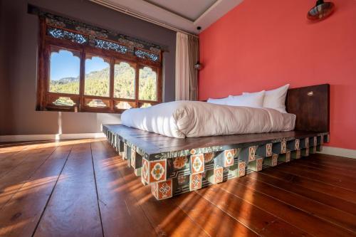 a bed in a room with a red wall at Taktsangri-La in Drugyel Dzong