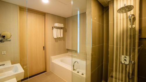 a bathroom with a shower and a tub and a sink at Incheon Airport Global Hotel & Suites in Incheon