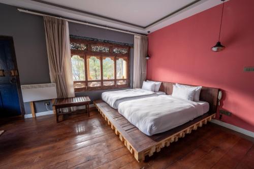 a bedroom with a bed in a red wall at Taktsangri-La in Drugyel Dzong