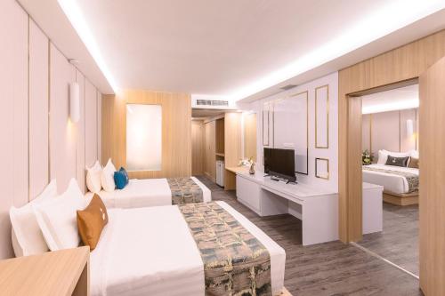 Una habitación de hotel con dos camas y un televisor. en โรงแรม จอมเทียน ฮอลิเดย์ พัทยา, en Jomtien Beach