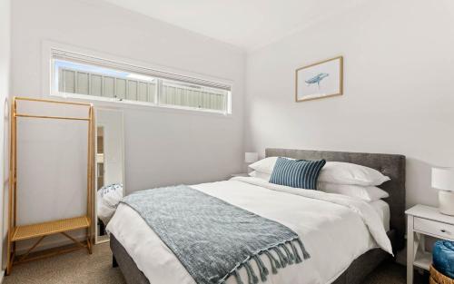 a white bedroom with a bed and a window at Modern Beachhouse, sea views in McCracken