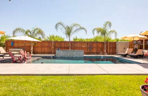 a swimming pool in a yard with chairs and umbrellas at County Poolhouse 20 Min SMF UC Davis Campus in Woodland