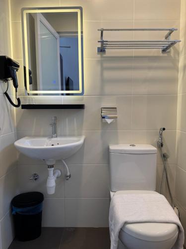 a bathroom with a sink and a toilet and a mirror at Maca Hotel by Sky Hive in George Town