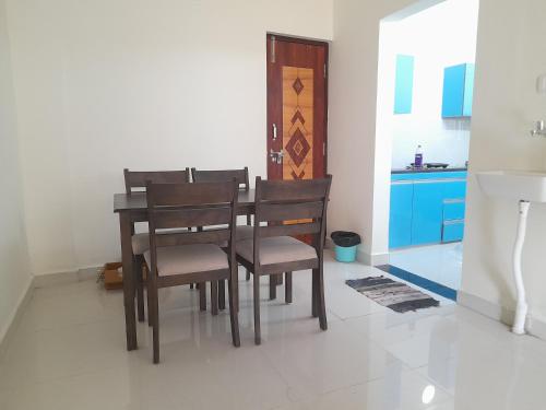 a dining room with a table and chairs and a kitchen at SathyaBama Mohan Illam in Chennai