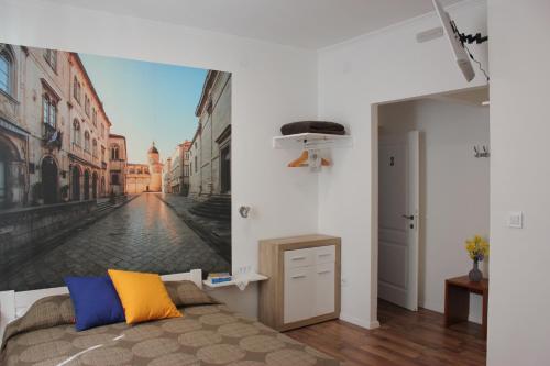 City Break Dubrovnik Apartments في دوبروفنيك: غرفة نوم بسرير ولوحة على شارع