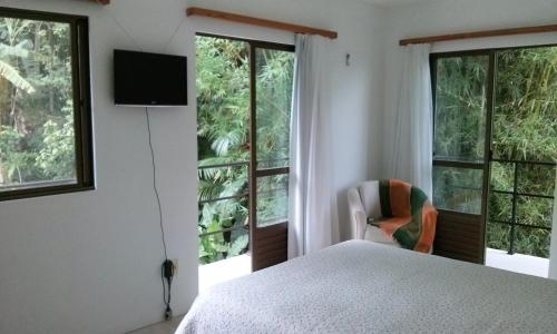 a bedroom with a bed and a tv and windows at Morada Colibri in Gamboa