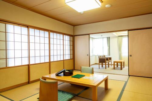 an empty room with a table and chairs and windows at Suizansou in Toyooka