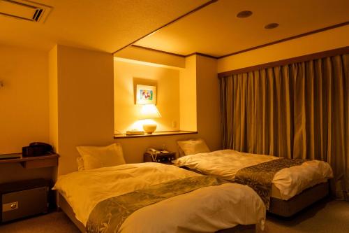 a hotel room with two beds and a window at Suizansou in Toyooka