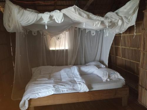a bed with a canopy and white sheets at Yenaduak Guest House in Dokkor