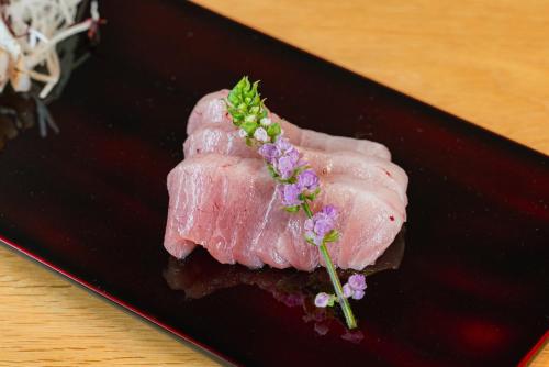 a piece of meat on a black plate with flowers on it at 湯の里いけもり別館 天座 in Himi