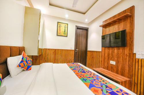 a bedroom with a bed and a tv on a wall at FabExpress Shri Sai DX - Nr Adarsh Nagar Metro in New Delhi