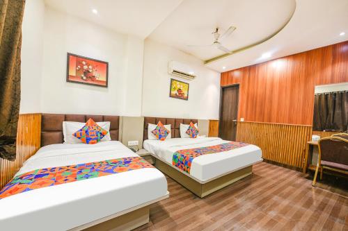 a hotel room with two beds and a desk at FabExpress Shri Sai DX - Nr Adarsh Nagar Metro in New Delhi