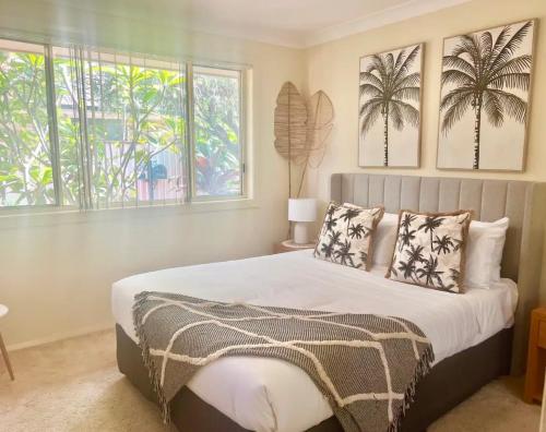 a bedroom with a large bed with two windows at FantaSea in Ettalong Beach