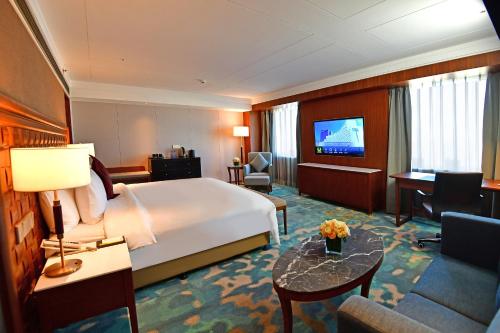 a hotel room with a large bed and a television at V-Continent Beijing Parkview Wuzhou Hotel in Beijing