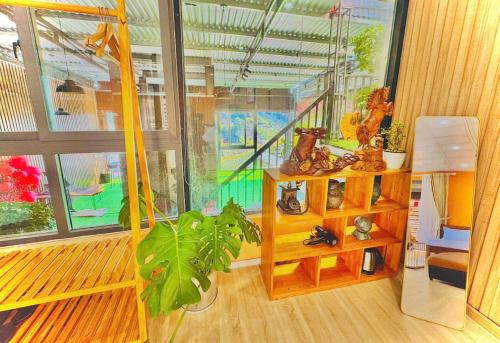 a living room with a large window and a plant at Pine Forest House Dalat in Xuan An