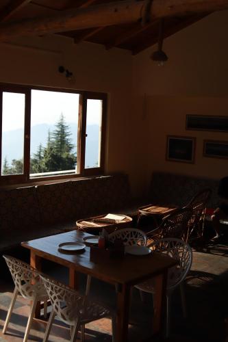 a table and chairs in a room with windows at Simba Jungle Lodge, Binsar Wildlife Sanctuary in Binsar