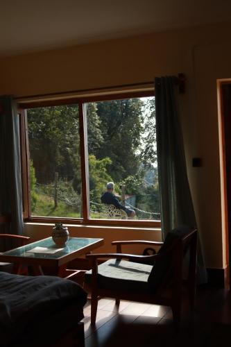 a man looking out the window of a living room at Simba Jungle Lodge, Binsar Wildlife Sanctuary in Binsar