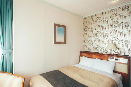 a hotel room with a bed and a wall at Kakegawa Grand Hotel in Kakegawa