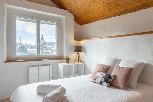 Un dormitorio con una cama blanca con una ventana. en Le Refuge proche de Genève, en Viry
