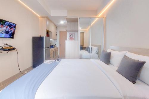 タンゲランにあるRestful and Cozy Living Studio Apartment at B Residence By Travelioの冷蔵庫付きの客室で、白い大型ベッド1台が備わります。