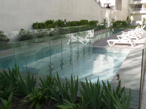 a swimming pool in a building with white chairs at Santiago Neighborhood in Santiago