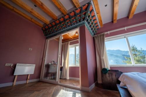 a bedroom with purple walls and a large window at Taktsangri-La in Drugyel Dzong
