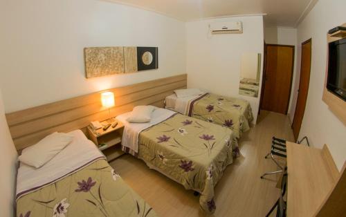 a hotel room with two beds and a table at Hotel Castro Mendes in Campinas