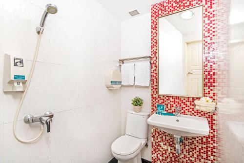 a bathroom with a toilet and a sink and a mirror at Hotel 81 Kovan in Singapore