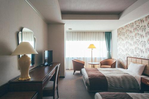 a hotel room with a bed and a desk and a window at Kakegawa Grand Hotel in Kakegawa
