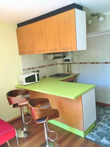 a kitchen with a green counter and some stools at Tribu Malen Apartamentos in Temuco