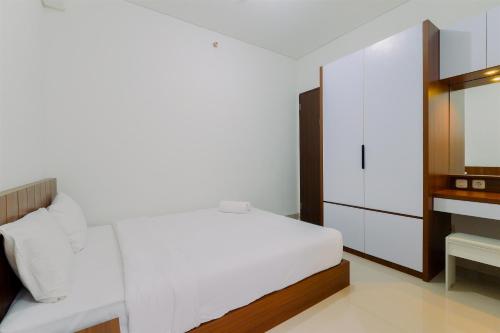 a bedroom with a white bed and a dresser at Great Location and Comfy 2BR Transpark Cibubur Apartment By Travelio in Depok
