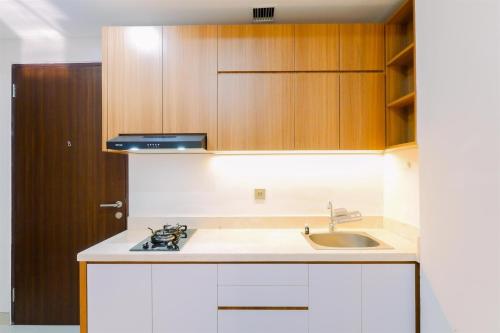 a kitchen with a sink and wooden cabinets at Great Location and Comfy 2BR Transpark Cibubur Apartment By Travelio in Depok