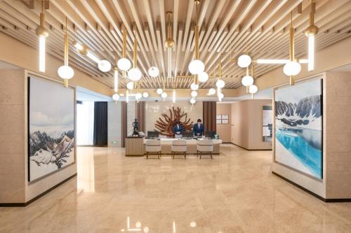 a lobby with tables and chairs in a building at Sha Zhi Ye Serviced Apartment Hotel - Houjie Wanda Plaza Liaoxia Subway Station in Dongguan