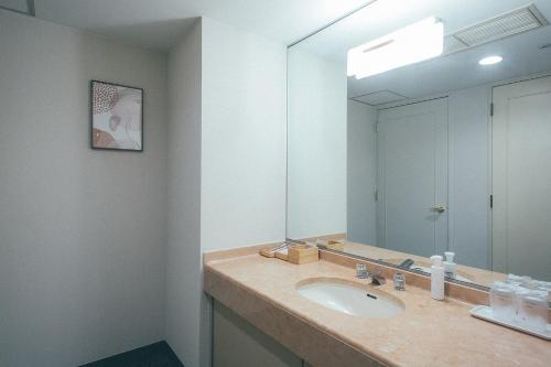 a bathroom with a sink and a large mirror at Kakegawa Grand Hotel in Kakegawa