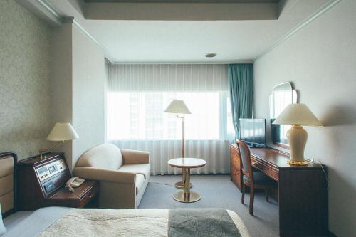 a hotel room with a bed and a desk and a television at Kakegawa Grand Hotel in Kakegawa