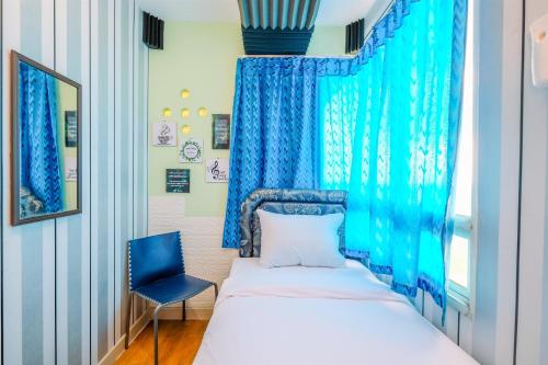 a bedroom with a bed and a blue curtain at Nice Comfort 2BR at Cinere Bellevue Suites Apartment By Travelio in Depok
