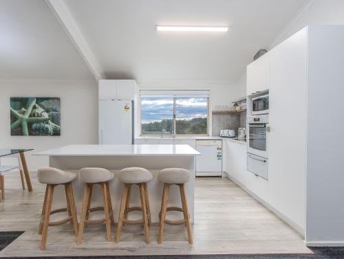 a kitchen with a large white island and stools at THE SHED - Tallebudgera Valley in Tallebudgera