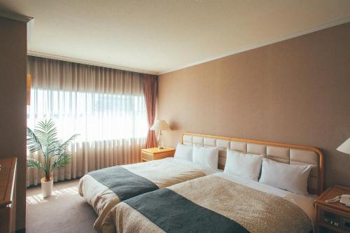 a bedroom with a large bed with a large window at Kakegawa Grand Hotel in Kakegawa